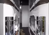 Et moderne, elegant vandrerhjem med to rader med hvite soveputer. Hver pod har en kromfinish, sengetøy og et vindu. Gulvet er mørkt tre, og den generelle atmosfæren er ren og minimalistisk.